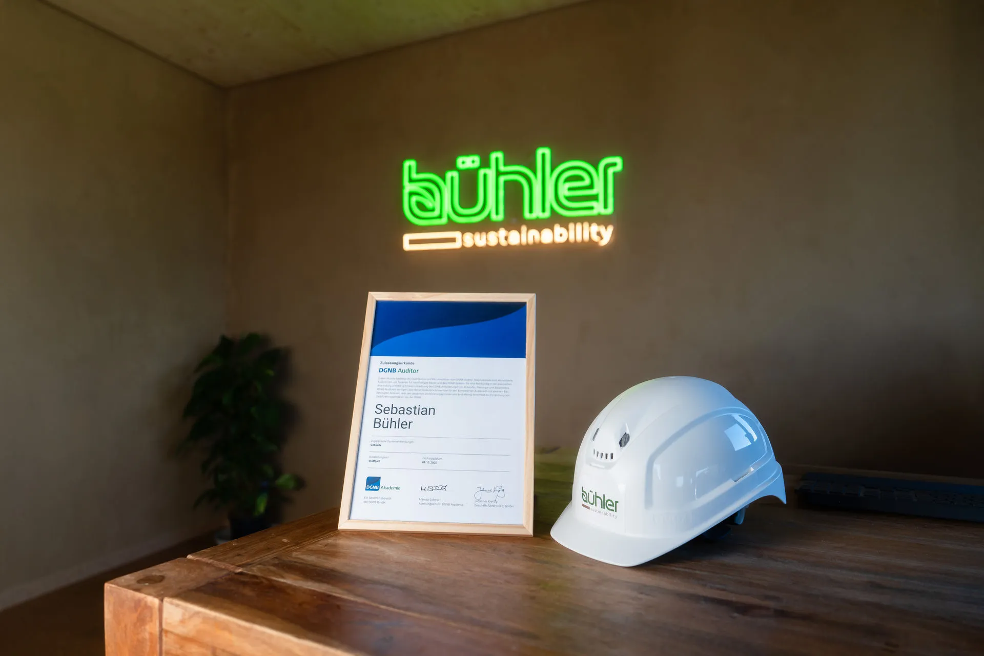 DGNB-Auditor-Zertifikat und Bühler-Schutzhelm im Büro